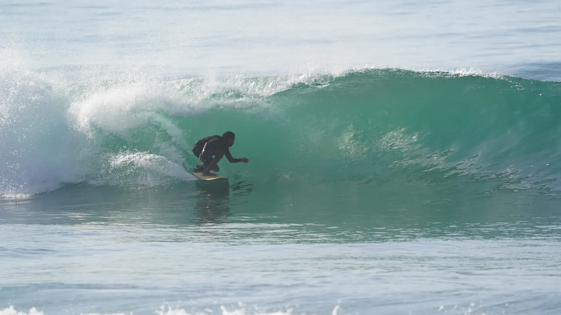 Surfer tucked inside a hollow, breaking wave