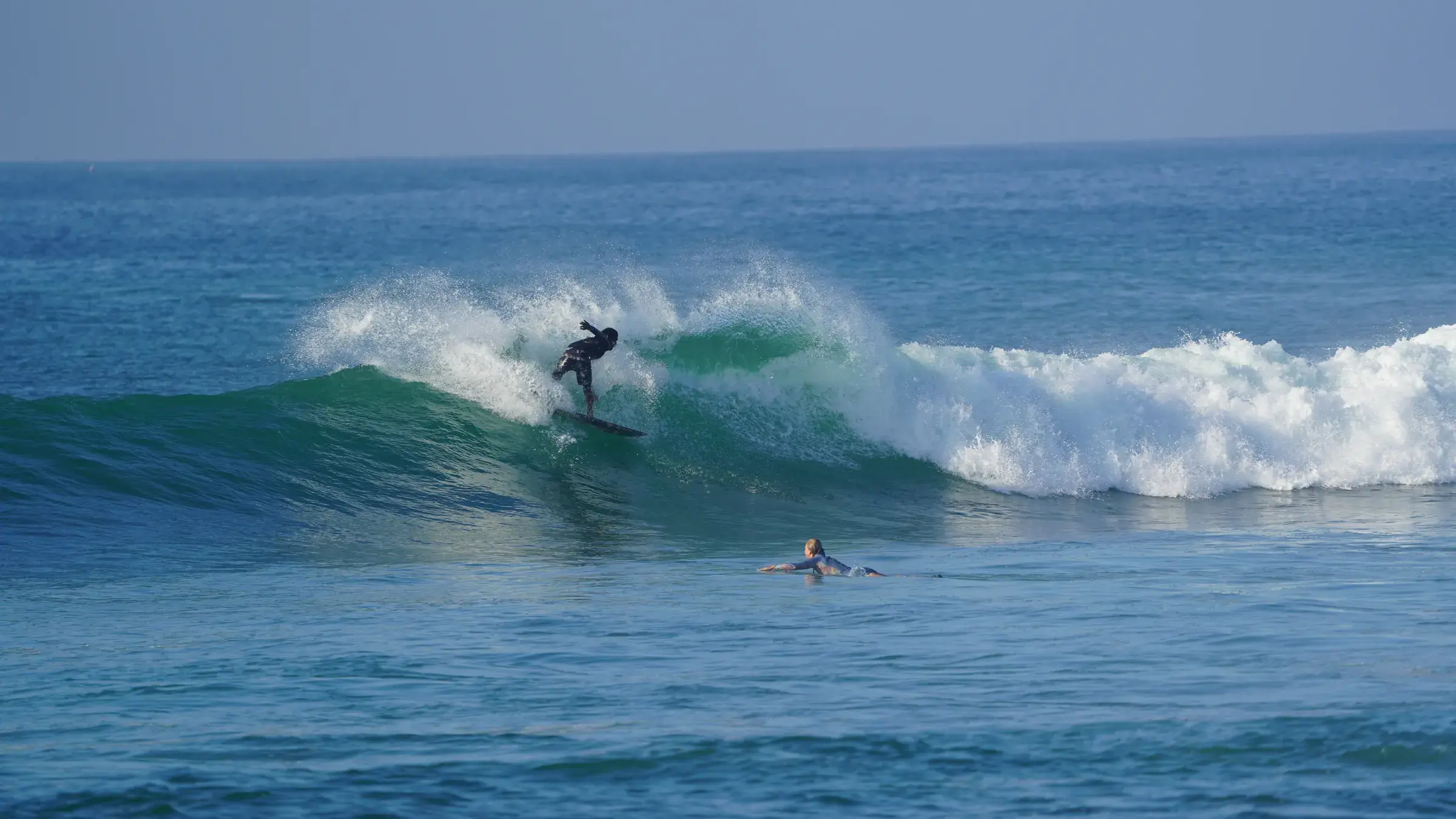 A surfer riding along a breaking wave, open blue sea behind