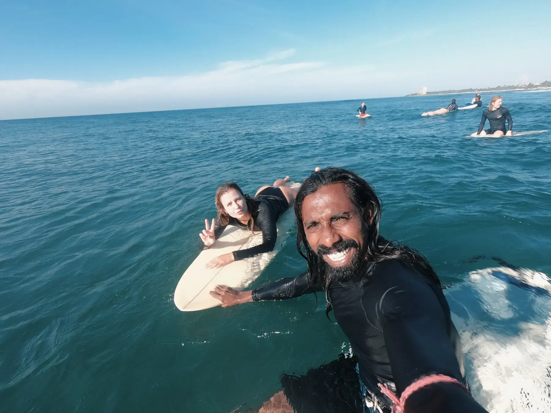 Instructor and student smiling out in the water, the student lying on a board