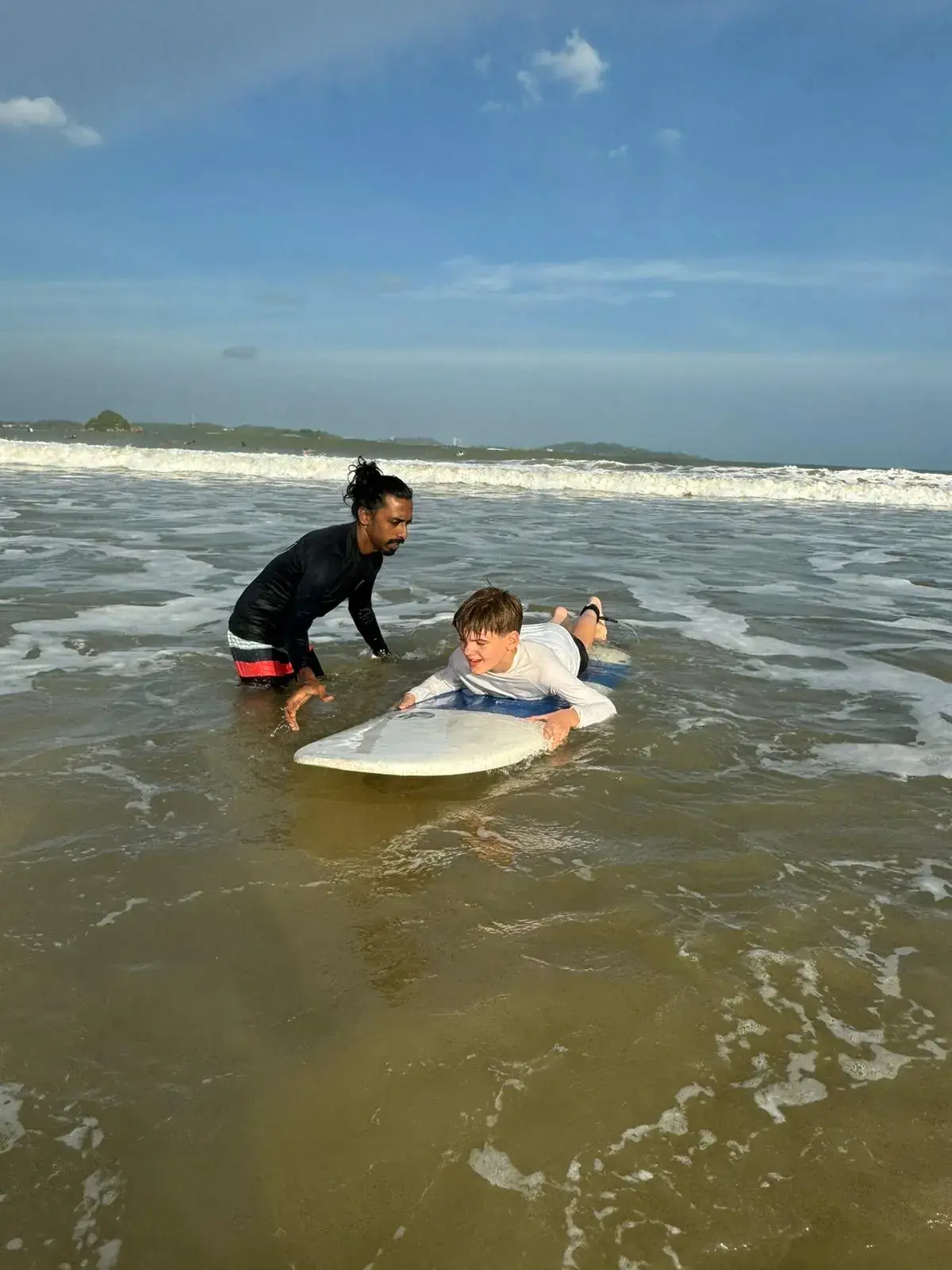Instructor steadying a student’s board in the shallows