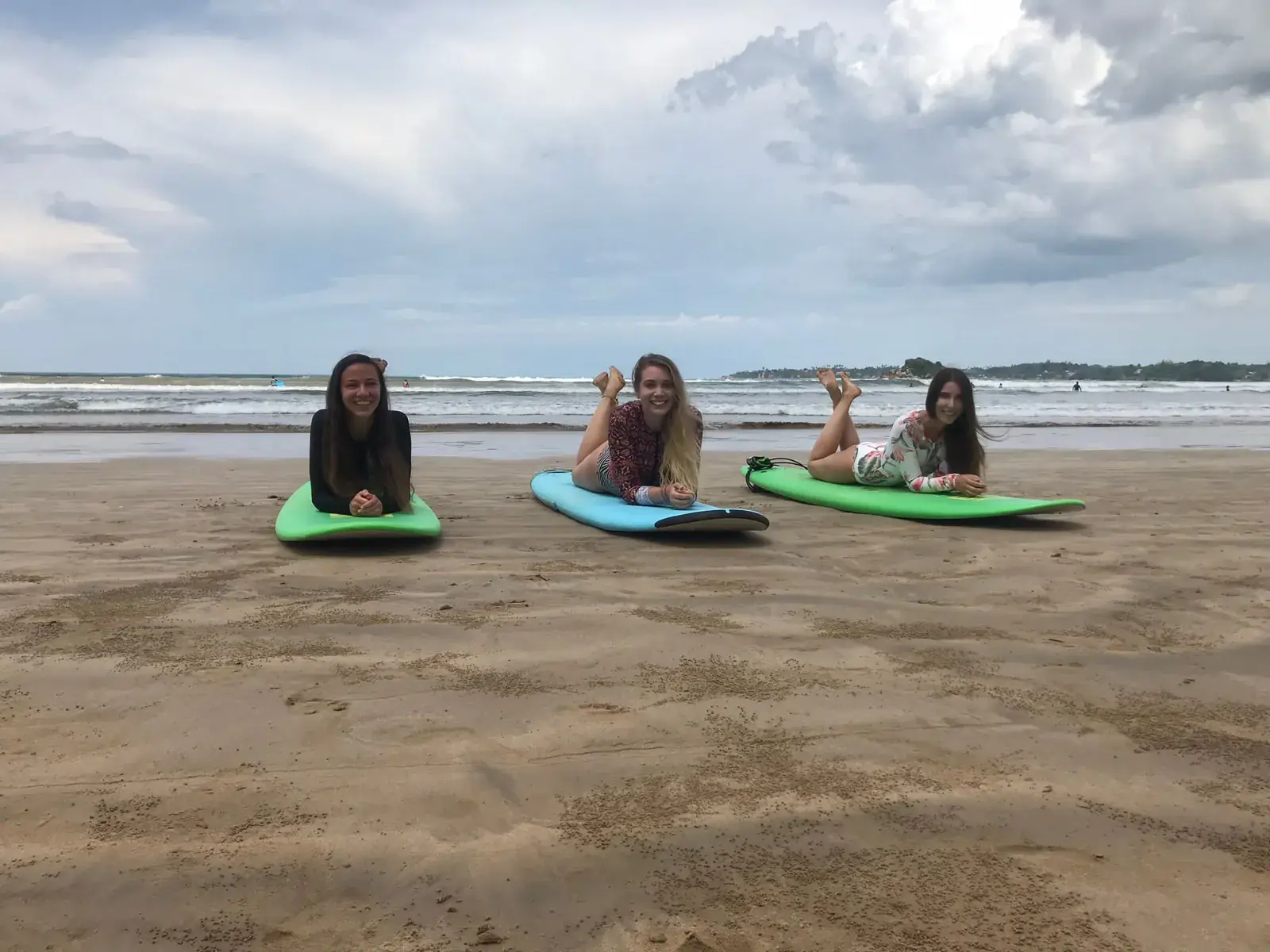 Three students practising the pop-up on their boards on the sand