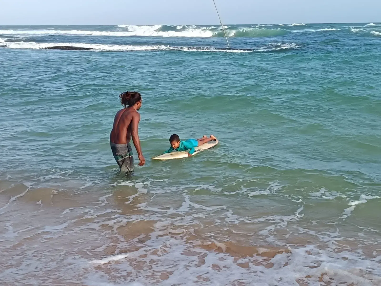 Instructor pushing a student onto a wave