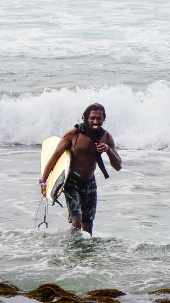 Surfer walking out of the surf with a board under one arm