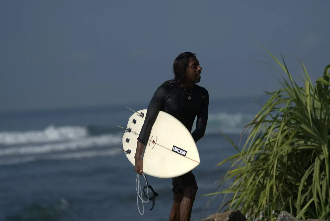 Surfer with a board under one arm by the sea