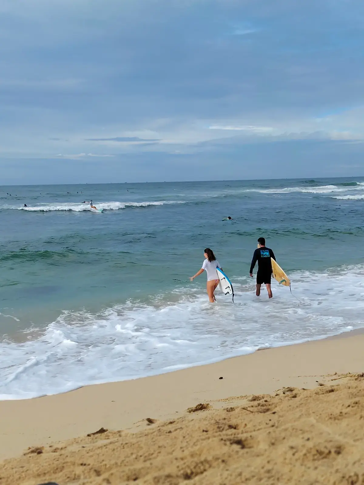 Two surfers walking into the sea with their boards