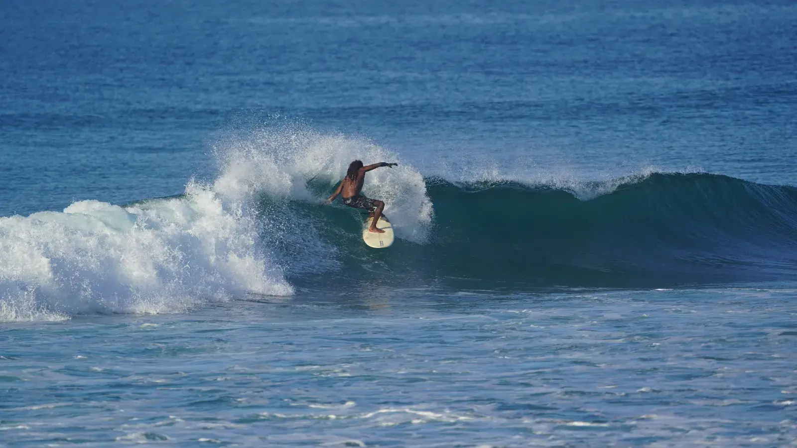 Surfer riding the face of a blue wave