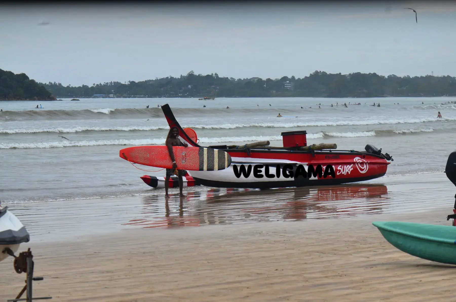 Red boat with Weligama painted on its side, on the beach