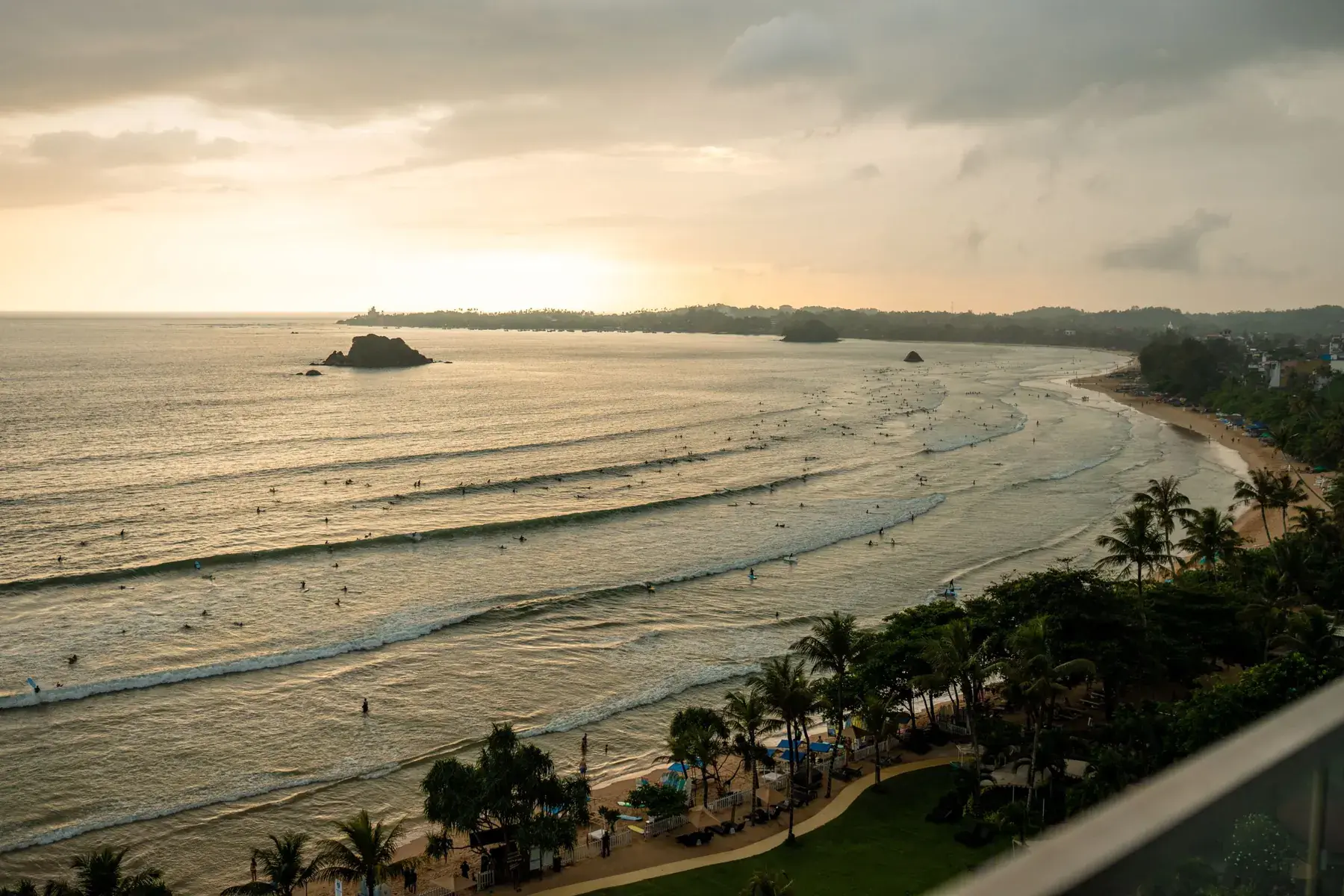 Surfers waiting in the lineup at Weligama Bay at sunset